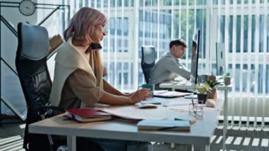 Açık uzay ofisinde cep telefonuyla konuşan meşgul bir yönetici. Bilgisayara benzeyen aktif bir kadın modern akıllı telefondan iş görüşmesi yapıyor. İş kadını, iş arkadaşı ve iş arkadaşı.