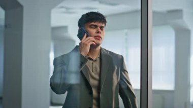 Stresli yönetici cep telefonuyla ayakta duran cam toplantı odasında bağırıyor. Kızgın iş adamı modern ofis binasının içinde akıllı telefonla tartışıyor. Öfkeli girişimci telefon konuşmasını duygusal olarak bitiriyor.