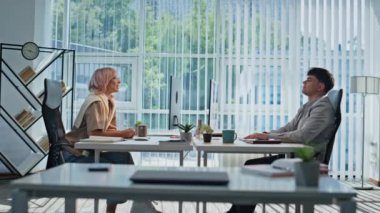 Ajansta mola veren rahat iş arkadaşları. Dinlenen adam, kadınla büyük masada bilgisayarlarla iletişim kuruyor. İş çifti iş yerinde rahat rahat oturup fikir alışverişinde bulunuyor. Takım çalışması konsepti 