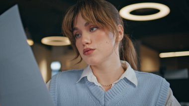 Masa başı modern ofis kapanışında çalışan odaklanmış kadın yönetici belgeleri arıyor. Çekici bir bayan işçi masada oturmuş, kapalı alandaki iş belgelerini inceliyor. Şirket çalışanı işyerindeki görevleri çözüyor