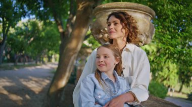 Sevgi dolu anne, Sunny Park 'a yakın mesafeden bakan çocuğu kucaklıyor. Mutlu gülümseyen anne küçük kız şehir bahçesinde yürüyor. Şık aile elbiseleri giyen rahat kadın doğada birbirine bağlanıyor gibi görünüyor.