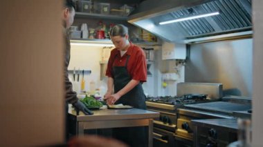 Profesyonel mutfakta işbirliği yapan iki şef yemek hazırlıyor. Modern mutfaklarda sebze doğrayan deneyimli bir erkek stajyere öğretmenlik yapıyor. Lokanta çalışma alanında aşçılık ekibi aşçılık süreci.