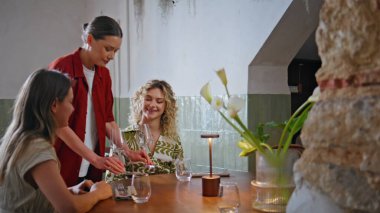 Restoran toplantısında garson tarafından servis edilen gülümseyen kadınlar. Kıvırcık saçlı bayan kafeteryada arkadaşıyla gevşemiş öğle yemeğinin tadını çıkarıyor. İki bayan meslektaşım rahatça sohbet ediyorlar. Dostça bir buluşma..