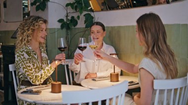 Lokantada şarap kadehleriyle kadeh kaldıran üç kadın. Kutlama anında arkadaşlarıyla içki içerek gülümseyen kızlar. Mutlu bayanlar dostça takılmayı sever..