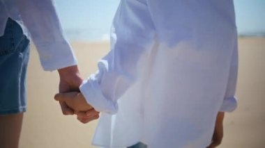 Yakın çekim annesi, güneşli sahilde yürüyen sevimli çocuğun elini tutuyor. Bilinmeyen şefkatli anne oğluyla kaynaşıyor rüzgarlı yaz deniz kıyısında birlikte dolaşıyorlar. Genç bir kadın kıyıda sevimli bir çocukla mutlu vakit geçiriyor..