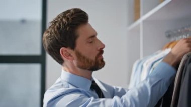 Ofisteki adam kıyafetleri seçerken gardıroba yakın çekim yapıyor. Sakallı adam resmi takım elbise alıyor ve sabah evinde işe hazırlanıyor. Randevudan önce rahat bir dairede ne giyeceğini düşünen biri. Moda yaşam tarzı 