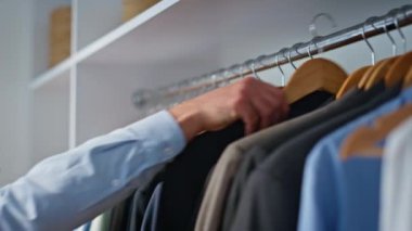 Erkek eller büyük gardıropta kıyafet seçiyor. Ofisteki adam iş için kıyafet hazırlıyor. Resmi takım elbiseli bir askı tutuyor. Özel odada aynaya bakan bir iş adamı. 