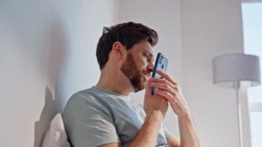 Endişeli adam yatakta cep telefonunu arıyor. Üzgün, ağlayan esmer, konuşan, akıllı telefonlu, hafta sonu rahat beyaz bir yatakta başını ovuşturan. Evde cep telefonuyla konuşan kırık bir adam. 