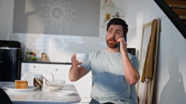 Rahatlamış bir adam kahvesini yudumlarken mutfaktaki akıllı telefonu arıyor. Apartman mutfağında oturan pozitif adam cep telefonuyla sabah içkisini içiyor. Sakin erkek kahvaltıda telefonda haberleri tartışıyor. 