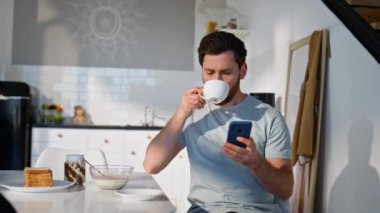 Odaklanmış işadamı, elinde cep telefonu olan bir espresso içiyor. Tıraşsız adam lüks bir dairede kahve yudumlarken cep telefonu görüntüsü alıyor. Sakallı adam akıllı telefon e-postalarını okuyor. 