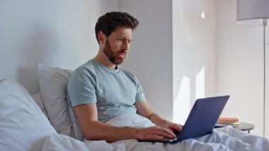 Stresli yönetici yatak odasında çalışıyor, sabahları bilgisayar ekranına bakıyor. Laptop kullanan esmer serbest yazar dosyada hata buldu. Sinirli adam güneş ışığı odasında dijital cihaz kapağını kapatıyor. 
