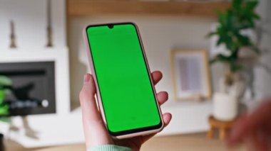 Oturma odasındaki krom tuşlu akıllı telefondan el kulaklığı takan bir kız. Kimliği belirsiz bir kadın evdeki yeşil ekran cep telefonundan alışveriş yapıyor. Kapalı alandaki model cep telefonunda bayan gezinme uygulaması.