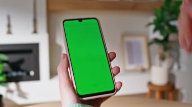 Bayan Parmaklıklı Model Cep Telefonu Ev-Kapanışı 'nda online alışverişleri seçiyor. Kimliği belirsiz bir kadın yeşil ekran cep telefonunda alışveriş uygulamasına bakıyor. İş kadını Chroma tuşlu akıllı telefonu okuyor.