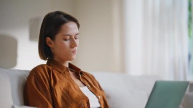 Rahat bir başlangıç bilgisayarı, rahat bir kanepede oturuyor. Genç kadın bilgisayar işçisi apartman kanepesinde proje yaratıyor. Sakin kız öğrenci uzaktan bilgisayar ekranına bakıyor.