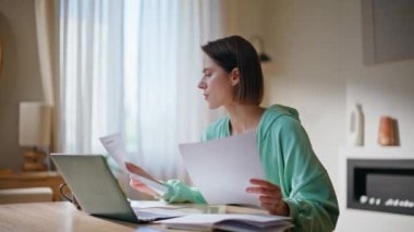Evinde evrak okurken gülümseyen bayan. Yakın çekim. Mutlu kadın girişimci dizüstü bilgisayar işyerinde oturan aylık bütçe raporunu beğendi. Başarılı kadın serbest çalışan iş sözleşmesini gözden geçiriyor..