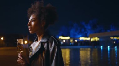Kaygısız kadın gece vakti zarif bardaktan şarap içiyor. Açık hava partisinde şampanya kadehiyle dans eden gülümseyen Afrikalı Amerikalı kız. Hafta sonu içkisini yudumlayan mutlu kadın.