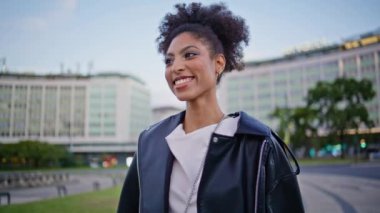 Rüzgâr estiren kıvırcık saçlarıyla sokakta gezinen güzel bir kız. Güzel afro-amerikan kadın, yürüyen şehirde gülümsüyor. Kaygısız mutlu bayan turist şehir meydanına yalnız çıkıyor..
