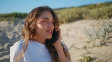Güneşli kadın Wild Beach 'te cep telefonunu arıyor. Mutlu gülümseyen kız akıllı telefondan konuşuyor. Güler yüzlü haftasonu tatili. Neşeli kaygısız kadın Marine Grsy Hill 'de olumlu bir konuşma yapıyor. 