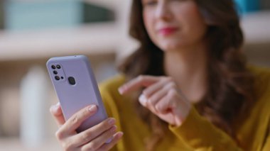 Cep telefonu haberlerini okuyan bir kadın yakın çekimde internet uygulamasına göz atıyor. Evde akıllı telefon kullanarak sosyal medyada sohbet eden gülümseyen kız. Ofiste cep telefonuyla alışveriş yapan pozitif serbest yazar..