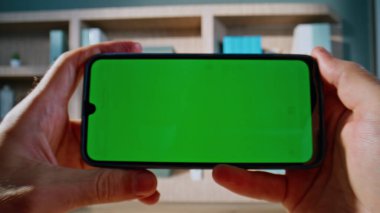 Yönetici cep telefonunun içeriğini takip ediyor. Ofiste mesai molası veriyor. Kapalı çekim. Bilinmeyen adam elleri yatay krom tuşlu akıllı telefonu tutuyor. İş adamı yeşil ekran telefonunda görüntüyü tarıyor.