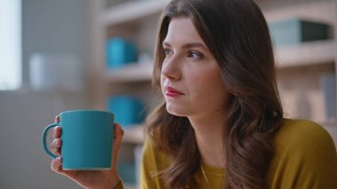 Modern ev iç mekanında kahve içen düşünceli bir kadın. Düşünceli iş kadını portresi ofiste çayını yudumlarken fikirler üzerine kafa yoruyor. Rahatlamış bayan menajer iş molası veriyor içeride kariyer yapmayı düşünüyor..