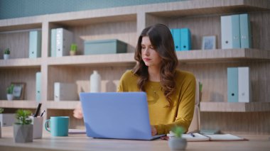 Yaratıcı yönetici, elinde kahve fincanı ile ofis masasında dizüstü bilgisayarla strateji üzerinde kafa yoruyor. Düşünceli iş kadını iş planı yapıyor. Ajans işyerinde kariyer düşünen ciddi kadın çalışanlar..