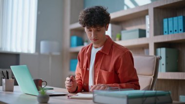 Ofis masasında dizüstü bilgisayar üzerinde çalışan profesyonel bir girişimci. Zeki geliştirici şirket işyeriyle ilgili not defterine not alıyor. Kıvırcık iş adamı yaratıcı şirkette işe başlıyor.