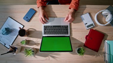 Ahşap masa üzerinde krom anahtar dizüstü bilgisayarı olan profesyonel serbest meslek sahibi bir işyeri. Kimliği belirsiz işadamı elleri yeşil ekran bilgisayarla modern ofis çalışma alanında yatıyor. Düzenli iş ortamı