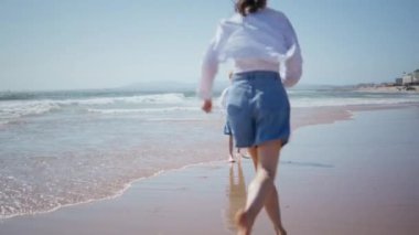 Anne, güzel sahil şeridinde oğlunun etrafında dolanıyor yaz tatilini sahilde geçiriyor. Mutlu anne ıslak ve güneşli bir günde sevgili çocuğa koşuyor. Kaygısız aile bir arada Deniz kıyısında dönüyorlar.