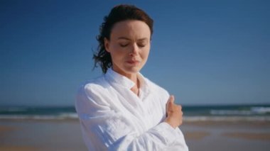 Düşünceli kadın sahilde durmuş, yaz melteminin tadını çıkartıyor. Güneşli deniz kıyısında dinlenen beyaz gömlekli düşünceli bir bayan. Portre, rahatlamış esmer okyanus manzarası hakkında yalnız hissediyordu..