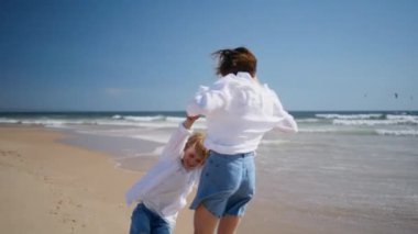 Yazın sahilde dönen çocuk annesi. Kumlu, güzel deniz kıyısında oğlunu oynayan mutlu kadın. Enerjik bir aile, okyanus dalgalarının keyfini çıkararak gülüyor. Sahilde hareketlilik.