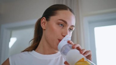 Rahat bir kadın, kapalı mekanda susuz kalmamak için su içiyor. Sağlıklı yaşam programında ferahlatıcı limonata içen güzel bir kız. Açık ev iç mekanında aktif yaşam tarzını destekleyen hidrasyon