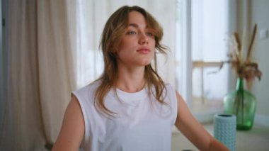 Modern apartman dairesinde sağlıklı bir vücudu ısıtan bir kadın spor paspasının üzerinde bacak bacak üstüne atarak oturuyor. Evde egzersiz yapan rahat bir bayan spor malzemelerinin etrafını sardı. Genç sporcu kadın pilates yapıyor..