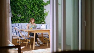 Rahatlamış kadın, etrafı sarmaşıklarla çevrili bir kanepede oturup kitap okumaktan zevk alır. Sabahın köründe terasta portakal suyu içen sakin bir bayan. Serene kız kanepede dinleniyor sayfaları çeviriyor..