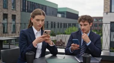 İş arkadaşları iş yerindeki şirket ortamında akıllı telefonlara odaklanıyor. İş arkadaşları, çatıdaki kafede cep telefonlarıyla mesajlaşıyorlar. İş kadını cep telefonlarıyla rahatlıyor.