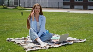 Kampüsün bahçesinde oturan neşeli kız cep telefonunu arıyor. Yeşil çimenlerin üzerinde telefonla konuşmaktan hoşlanan gülümseyen kadın öğrenci ders arası veriyor. Akıllı telefondan konuşan mutlu bayan laptopla battaniyeyi rahatlatıyor..