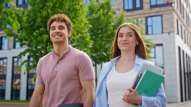 Kendine güvenen meslektaşlar, kapalı kapılar ardında güneşli bir günün tadını çıkaran defterlerle birlikte yürüyorlar. İki iş adamı modern binanın yakınlarında geziniyor. Kameraya bakıyor. Ders çalışmak için kitap taşıyan genç öğrenciler.