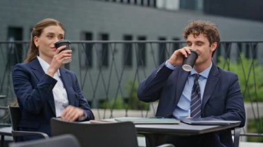 Rahat iş ortakları belediye binasının terasında birlikte kahve içiyorlar. Takım elbiseli iş arkadaşları dışarıda kahve içerek eğleniyorlar. Resmi olmayan toplantıda gülümseyen mutlu profesyoneller..