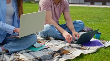 İş adamları parkta dizüstü bilgisayarlar yazarak battaniyeyi kapatıyorlar. Çim üniversitesi kampüsünde uzaktan eğitim gören iki rahat online öğrenci. Gülümseyen adam bilgisayarını kapatıyor. Uzaktan çalışmadan sonra vücudu geriyor..