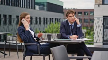 İş ortakları restoran terasını arıyor. Odaklanmış iş kadını dışarıda ciddi bir telefon görüşmesi yapıyor. Meslektaşlar iş görüşmelerini cep telefonlarıyla yapıyorlar..