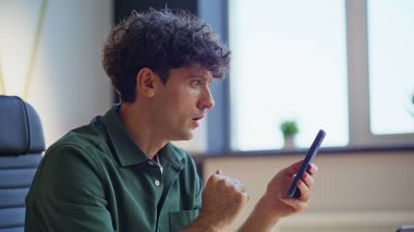 Harika bir yönetici cep telefonunda SMS okuyor modern çalışma alanını kapatıyor. Şaşırdım. Serbest çalışan evdeki akıllı telefondan haber yayını yapıyor. Kıvırcık girişimci ofisteki cep telefonu mesajından endişeli.