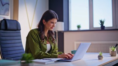 Çağdaş ev ofisinde dizüstü bilgisayar yazan kadın yazar. Ofiste fikirler üzerine makale yazan gülümseyen profesyonel gazeteci. Bilgisayarda çalışan iş kadını finansal başarıdan memnun