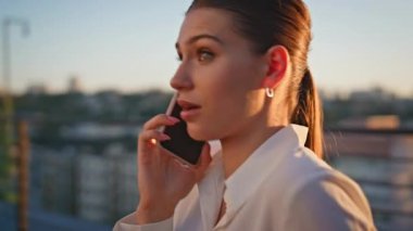 Sunset Terası 'nda iş meselesini konuşmak için arayan bayan. Endişeli bir kadın cep telefonuyla konuşuyor. Güneşin altında tek başına dikiliyor. Stresli iş kadını hoşnutsuz akıllı telefon konuşması.