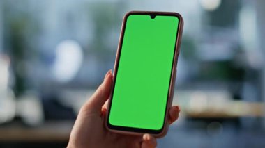 Manikürlü parmak tıklama yeşil ekran akıllı telefon iş yerindeki yakın planda online uygulamayı açıyor. Bilinmeyen bir kadın cep telefonundaki mesajlara göz atıyor. Krom anahtarlı cep telefonunu elinde tutan kadın.