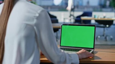 Yeşil ekran dizüstü bilgisayarda çalışan bir işletme yöneticisi. Açık alan arkası görüntüsü, yakın plan. Tanınmayan iş kadını, krom anahtar bilgisayarda geziniyor. Model bilgisayar aygıtında e-posta okuyan zarif bir kadın..