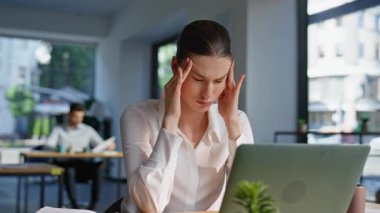 Gergin ofis çalışanı, modern çalışma alanlarında mesai yapan tapınaklara masaj yapıyor. Yorgun kadın yönetici projeksiyondan yoksun. Yorgun iş kadını kendini işyerinde çok çalışıyor hissediyor..