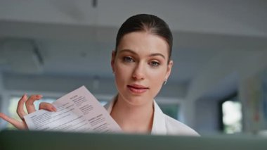 Endişeli bayan, iş yerindeki video görüşmesinde elinde belgelerle yakınıyor. Gergin iş kadını internette tartışıyor ve evrakları gösteriyor. Hayal kırıklığına uğramış kadın bilgisayarını kapatarak konuşmayı bitir.