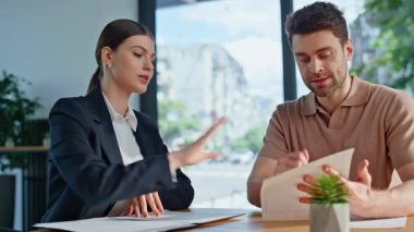 İki işletme yöneticisi ofis masasında oturup şirket anlaşmasını görüşüyor. Profesyonel iş kadını iş adamına kontrat detaylarını açıklıyor. İş arkadaşları şirket stratejisi üzerinde beyin fırtınası yapıyor.