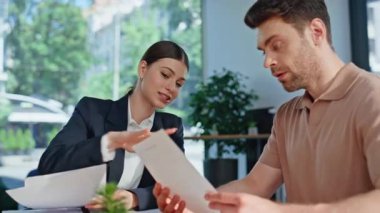 Modern kurumsal ofisteki finansal danışman danışman müşteriye yakın çekim. Pozitif iş kadını masada iş gazetelerini okuyan bir adamla konuşuyor. İşadamı yöneticiyle yatırım stratejisini tartışıyor