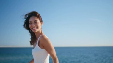 Yazın kıyı şeridini yöneten neşeli kız kapanış yapıyor. Kumsalda koşan parlak gülüşlü mutlu esmer kamera. Neşeli kadın deniz tatiline çıkıyor. Güzel okyanus kıyısında eğleniyor..